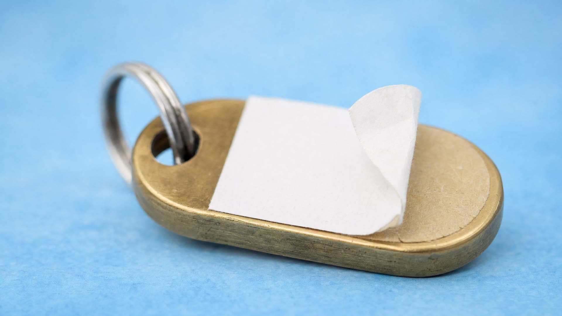 A key tag with a label peeled half off, blue.