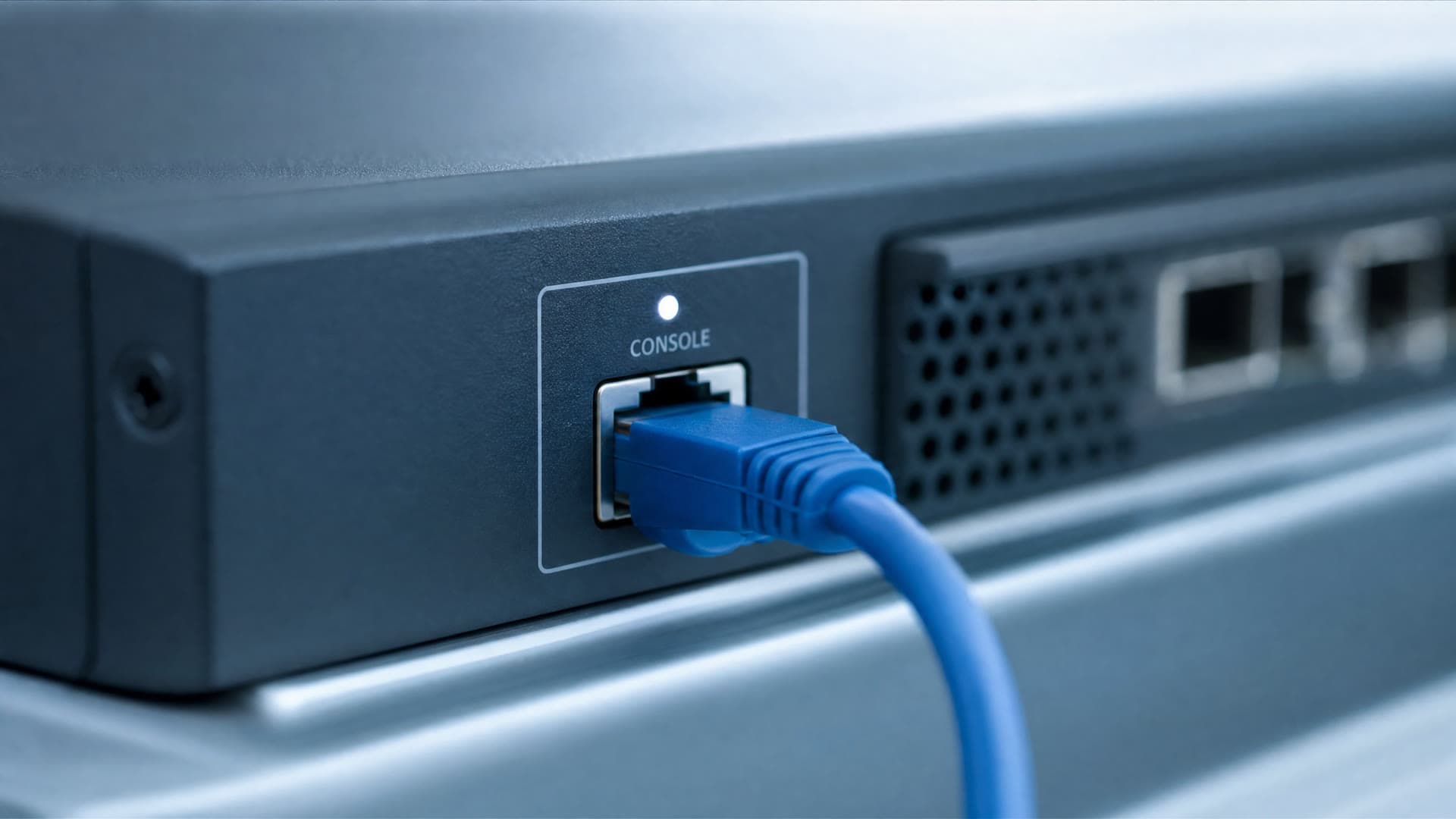 Close-up of a firewall's console port with a cable seated, shallow depth of field, blue tone.